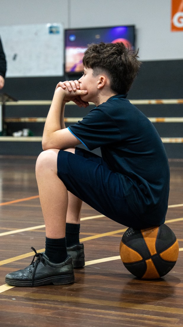 Student resting on a basketball between drills