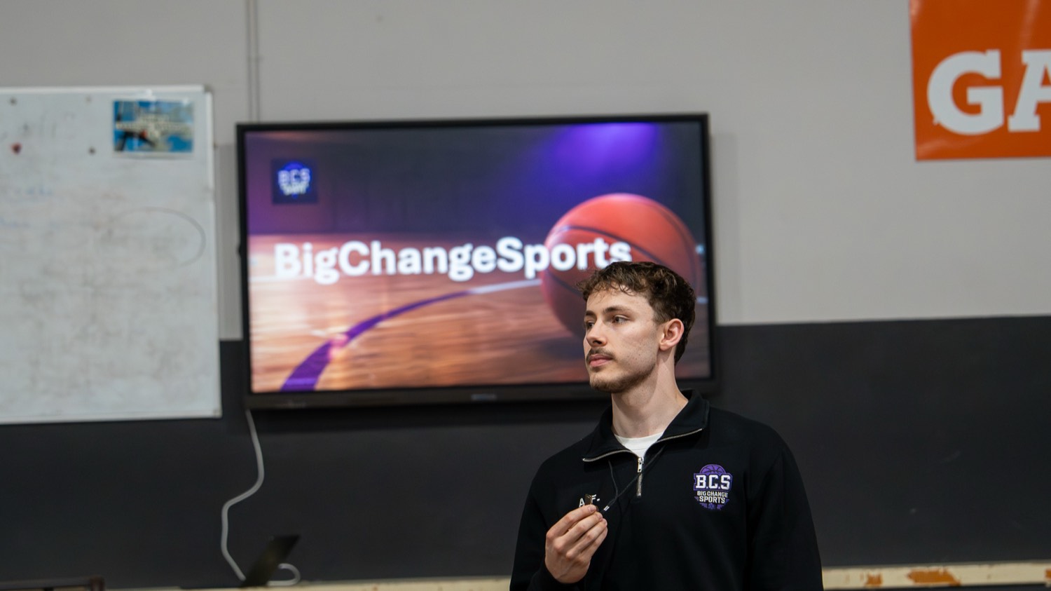 Coach leading a classroom discussion in front of a Big Change Sports presentation
